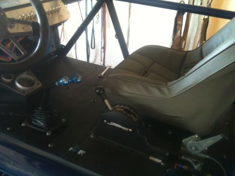 1966 Ford Bronco - The interior of a custom buggy shows a racing seat, steering wheel, and two shifters on the floor.