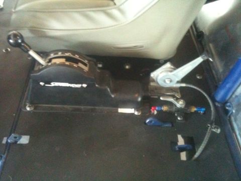 1966 Ford Bronco - The interior of a vehicle shows a shifter and seat, with the word "Steering" visible on the shifter console.