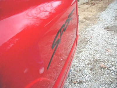 1997 Ford Taurus - A red car's side panel displays a black 'Sport' decal.
