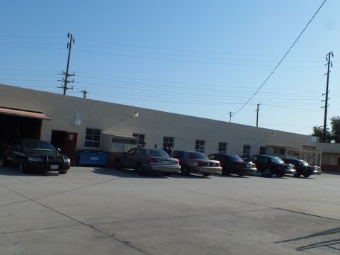 2003 Ford Crown Victoria - Several Panther-platform full-size sedans lined up against a tan warehouse wall with utility poles overhead.