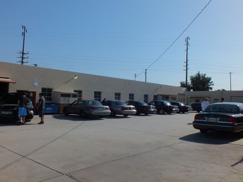 2003 Ford Crown Victoria - Sedans parked along a beige building, people near an open hood at left