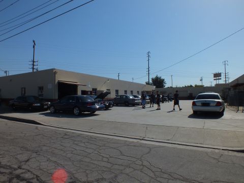 2003 Ford Crown Victoria - Group meet view, dark and silver sedans along a block building, attendees milling