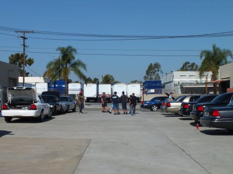 2003 Ford Crown Victoria - Attendees standing among parked Panther sedans, white truck trailers in background