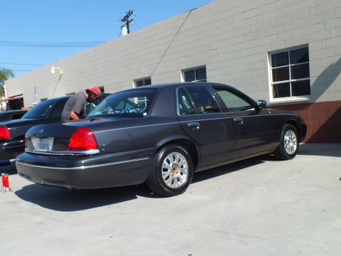 2003 Ford Crown Victoria - Dark gray Crown Victoria detailed by a man, machined wheels, parked at shop wall