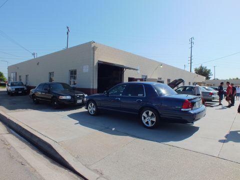 2003 Ford Crown Victoria - Dark blue Crown Victoria hood up near a garage bay, other sedans and people around