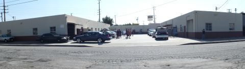 2003 Ford Crown Victoria - Far panoramic view of parked sedans and a small crowd between block buildings