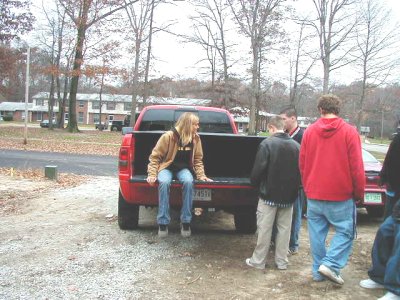 1997 Ford Taurus - A group of people stand around a red pickup truck on a cloudy day.