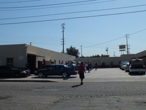 2003 Ford Crown Victoria - Meet view across a street, dark sedans and a wagon parked by shops, power lines above