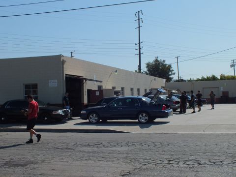 2003 Ford Crown Victoria - Dark blue Crown Victoria trunk open along a curb, attendees and shops behind