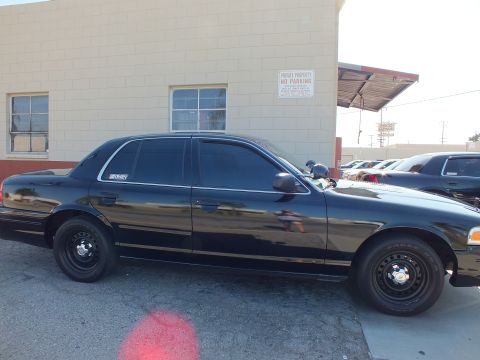 2003 Ford Crown Victoria - Blacked-out Crown Victoria sedan parked beside a building with a Private Property No Parking sign.
