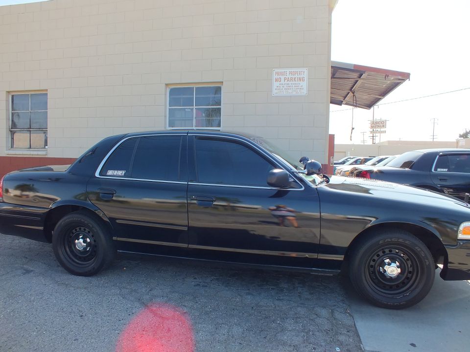 Black Ford Crown Victoria Police Interceptor side profile with steel wheels by warehouse