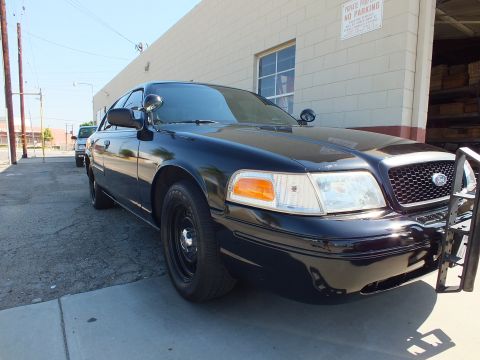 2003 Ford Crown Victoria - Front corner of a dark Ford Crown Victoria showing amber turn signals and chrome Ford oval grille.