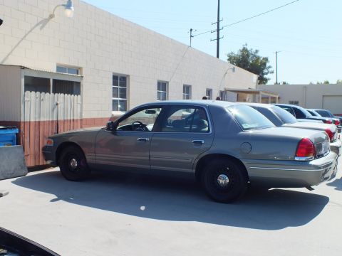 2003 Ford Crown Victoria - Gray full-size Mercury sedan parked along a row of cars next to an industrial building.