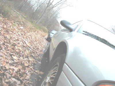 1997 Ford Taurus - Car driving on a dirt road covered in autumn leaves.