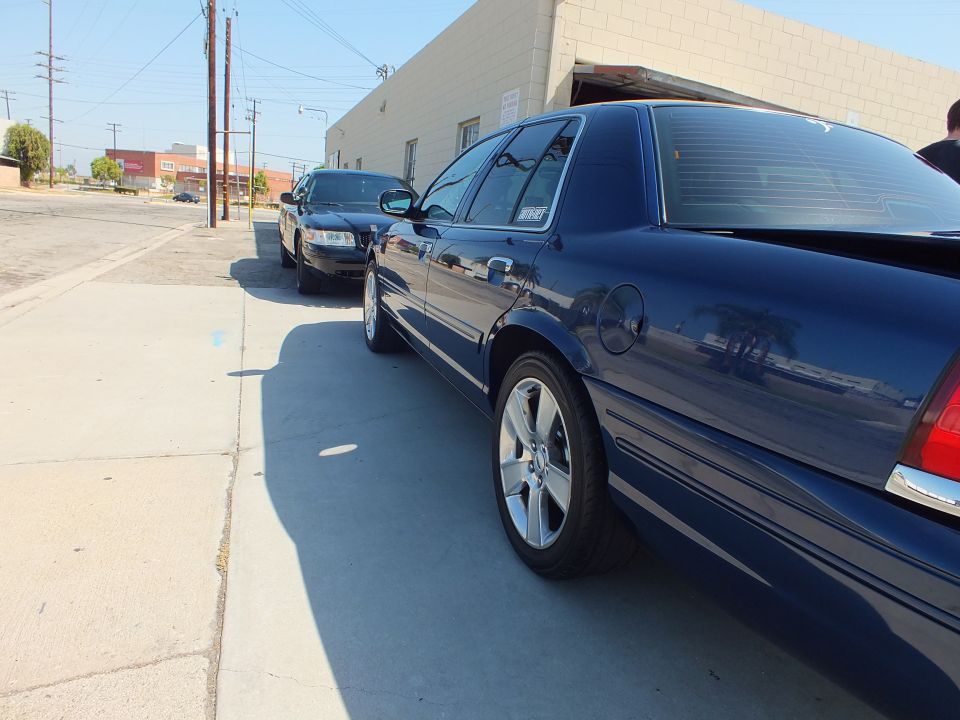 Dark blue Ford Crown Victoria sedan rear quarter on machine-faced alloy wheels in an industrial lot