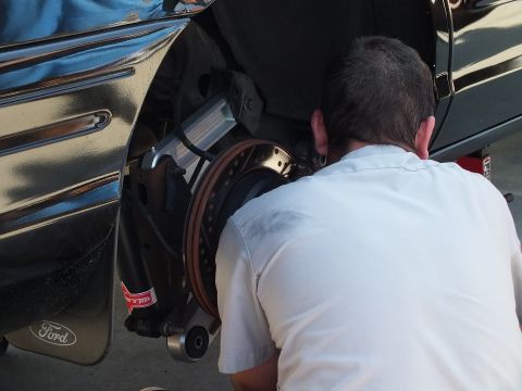 2003 Ford Crown Victoria - Close view of a person servicing a drilled front brake rotor on a black Ford sedan.