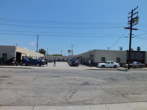 2003 Ford Crown Victoria - Street-level wide shot of a garage complex, cars including a white sedan parked along the lot, power lines overhead