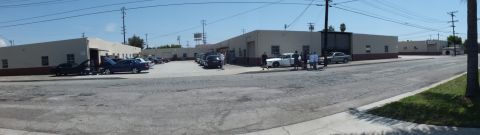 2003 Ford Crown Victoria - Distant panoramic of an industrial block, sedans parked along the lot and a cluster of people on the pavement