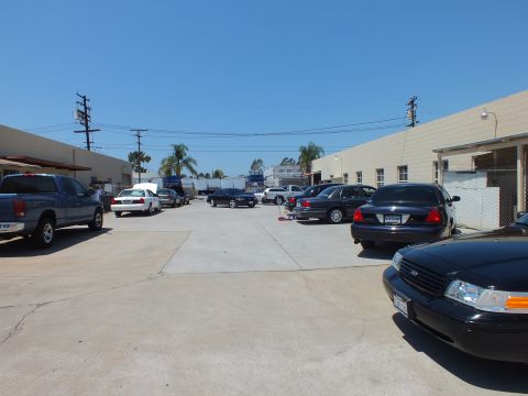 2003 Ford Crown Victoria - Wide lot view of parked Panther-platform sedans and a gray pickup, black Ford sedan in foreground
