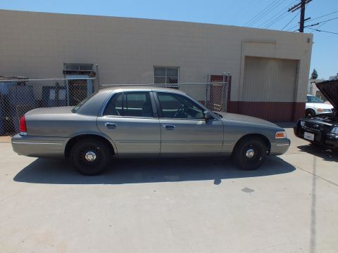 2003 Ford Crown Victoria - Side view of a gray-green Crown Victoria on black steel wheels parked at a warehouse loading dock