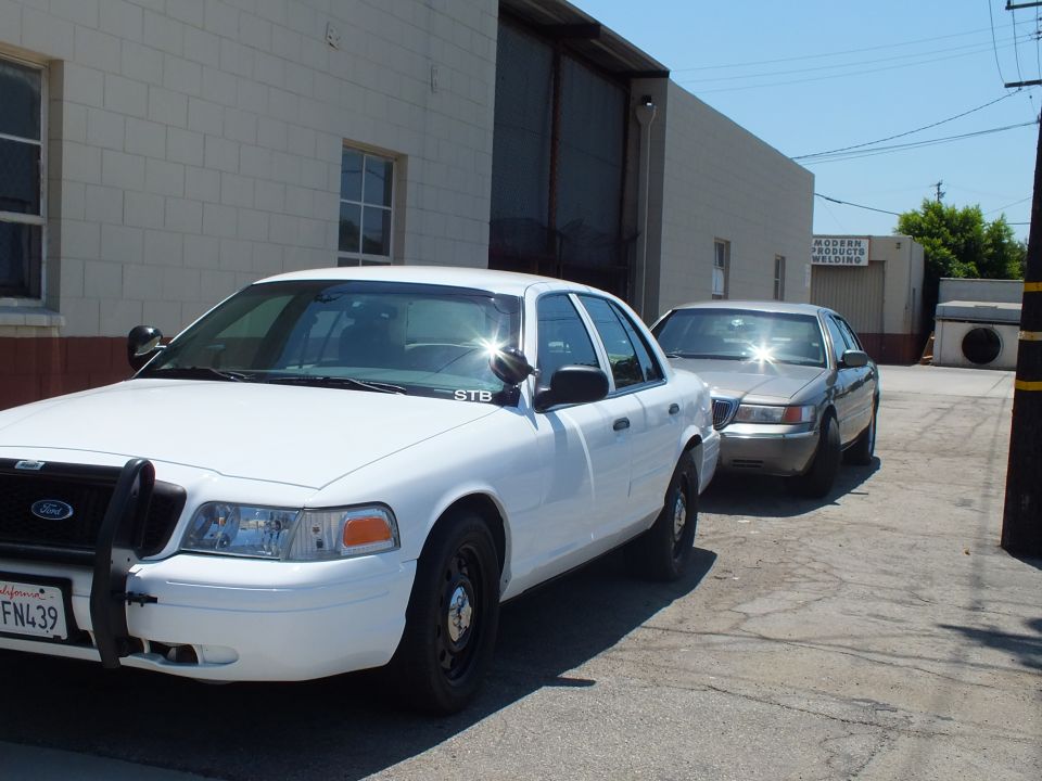 White Ford Crown Victoria with brush guard plate 6PFN439 and gray sedan in driveway