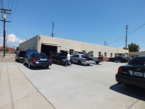 2003 Ford Crown Victoria - Several Ford Crown Victoria sedans gathered at a body-shop lot, hoods and trunks open while a person walks past.