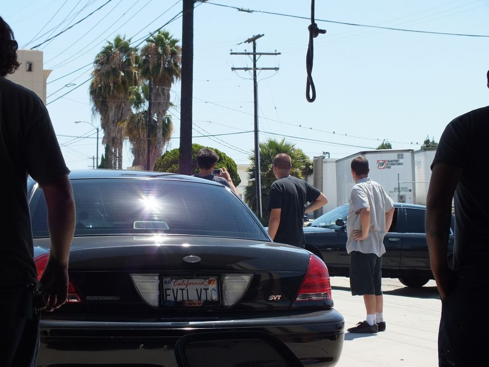 Rear of black Ford Crown Victoria SVT with California plate EVTL VTC and men behind