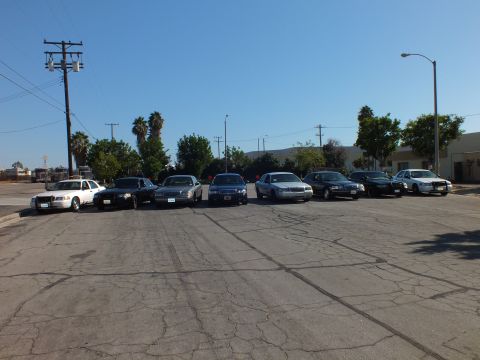 2003 Ford Crown Victoria - White, blue, and silver sedans line up front-on under power lines and clear sky.