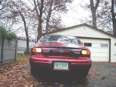 1997 Ford Taurus - Rear view of a red Ford Taurus parked in a driveway with a garage in the background.