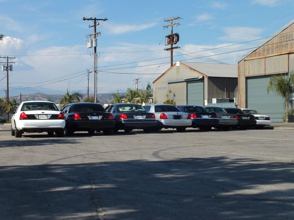 Row of Ford and Lincoln sedans parked in industrial lot under blue sky