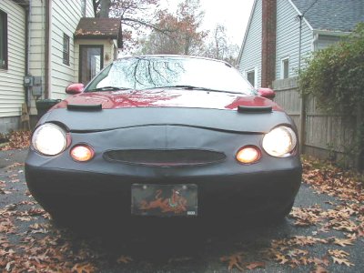 1997 Ford Taurus - Head-on view of a red Ford Taurus sedan with its entire front clip, bumper cover, hood front and headlight surrounds, in flat black primer,…