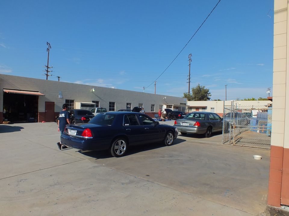 Dark blue Crown Victoria parked in shop yard near garage bays and fence