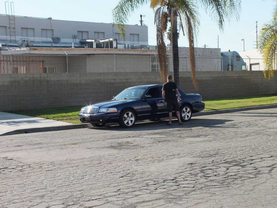 Dark blue Crown Victoria parked on street with man standing at open door