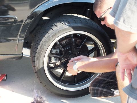 2003 Ford Crown Victoria - Close view of a black five-spoke wheel with machined lip while a person reaches to the center hub