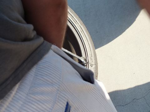 2003 Ford Crown Victoria - Over-the-shoulder view of a person reaching down to a silver wheel with a wrench, sneaker beside it
