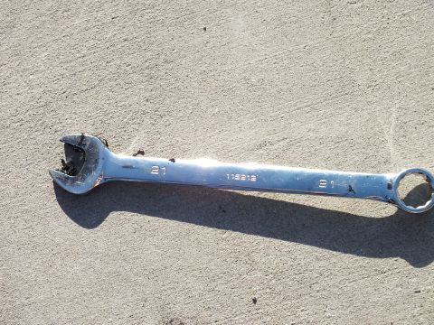 2003 Ford Crown Victoria - Close-up of a 21mm combination wrench stamped 115212, the open end rounded from use