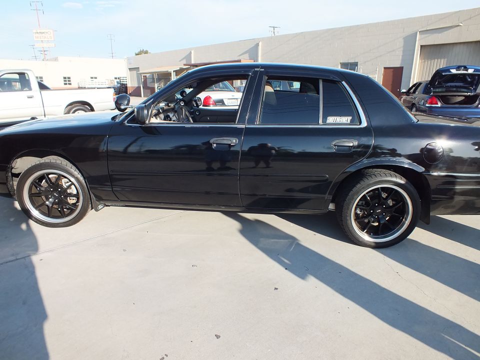 Black full-size sedan profile in lot with black multi-spoke wheels