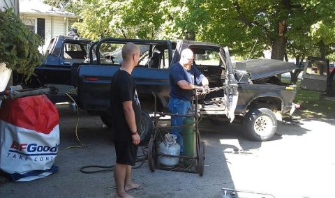 1979 Ford Bronco - Two men are working on a disassembled SUV, possibly a Ford Bronco, with a welding torch and gas tanks.