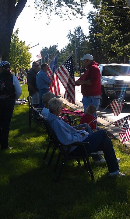 1979 Ford Bronco - A white pickup truck is visible behind a group of people gathered for an outdoor event with American flags.