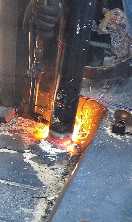 1979 Ford Bronco - Metal fabrication in progress with a cutting torch, sparks illuminate the work area.