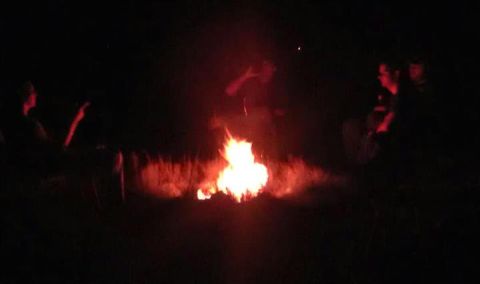 1979 Ford Bronco - A group of people gather around a bright campfire in the dark.