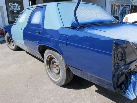 1991 Ford LTD Crown Victoria - A car undergoes a paint job, showing different shades of blue and masking tape on its body panels.