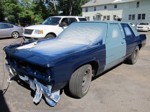 1991 Ford LTD Crown Victoria - A 1991 Ford Crown Victoria is being painted, with the front half in dark blue and the rear in primer gray. Another vehicle is visible in th…
