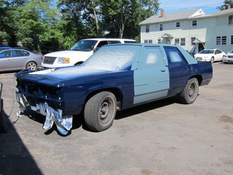 1991 Ford LTD Crown Victoria - A 1990 Ford Crown Victoria LTD is undergoing bodywork and painting outdoors.