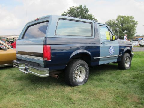 1991 Ford LTD Crown Victoria - Passenger-side view of a two-tone blue Ford Bronco with a round door emblem and chrome rear bumper on grass.