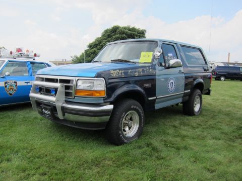 1991 Ford LTD Crown Victoria - Front-quarter view of a two-tone blue Ford Bronco with chrome push bar and door seal on a grassy show field.