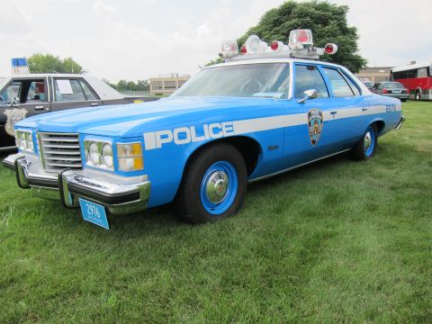 1991 Ford LTD Crown Victoria - light-blue Pontiac police sedan lettered POLICE with twin roof lights and chrome grille displayed on grass.