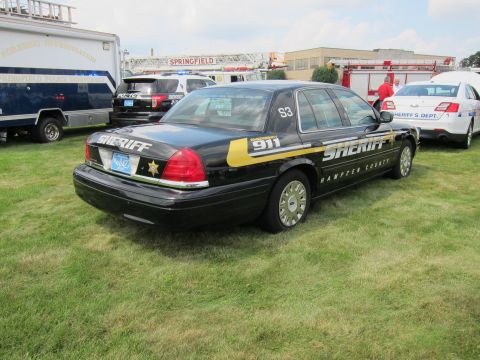 1991 Ford LTD Crown Victoria - Rear-quarter view of a black Ford Crown Victoria marked SHERIFF Hampden County 911 with gold star on a grass field.