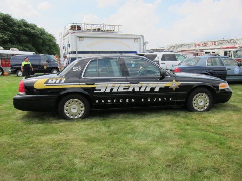 1991 Ford LTD Crown Victoria - Side profile of a black Ford Crown Victoria sheriff car lettered SHERIFF Hampden County 911 parked on grass.