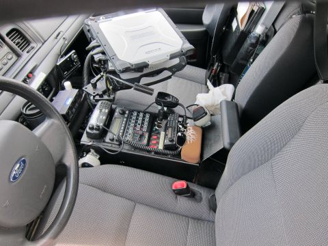 1991 Ford LTD Crown Victoria - interior of a police vehicle showing a Ford steering wheel, a rugged laptop on a center console mount, and radio control equipment.